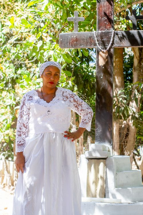 Free A woman in a white dress stands beside a wooden cross in an outdoor setting in Amarante, Brazil. Stock Photo
