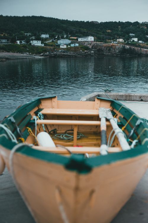 Free Charming wooden rowboat docked by a peaceful lakeside town, perfect for travel and nature enthusiasts. Stock Photo