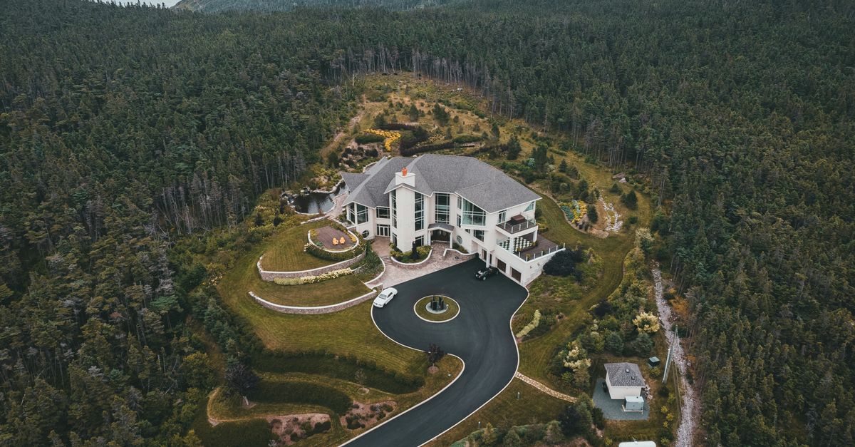 A stunning aerial view of a luxurious mansion surrounded by lush greenery and scenic countryside.