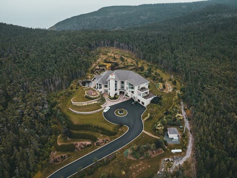 A stunning aerial view of a luxurious mansion surrounded by lush greenery and scenic countryside.