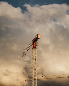 A construction crane rises against a dramatic cloudy backdrop, showcasing urban development.