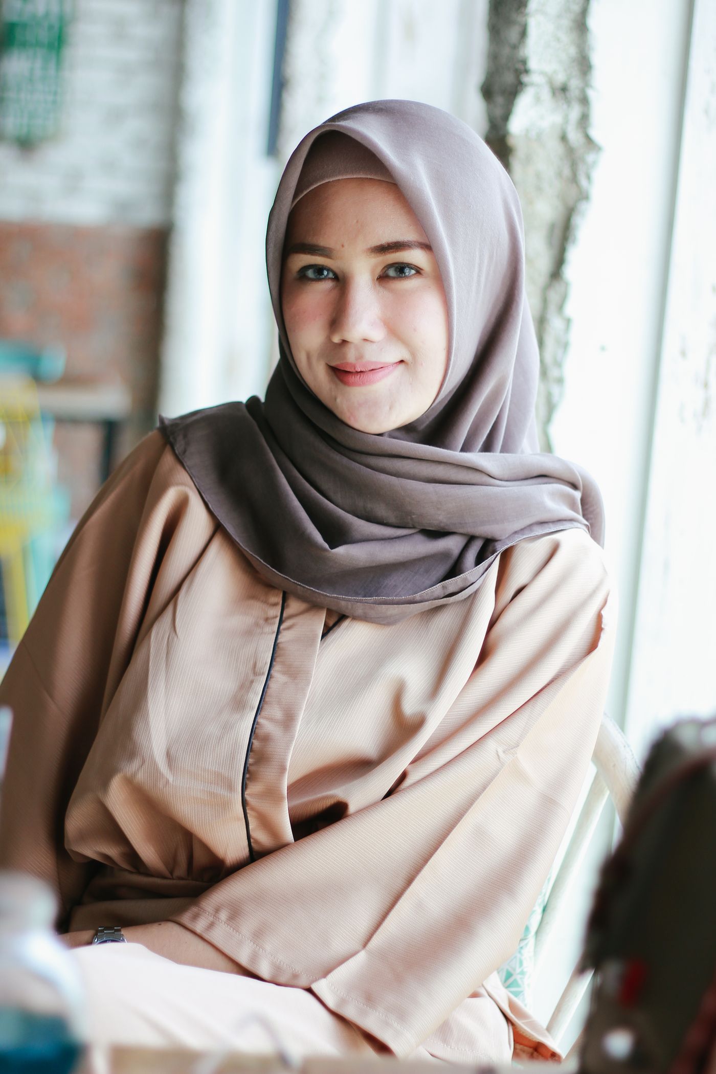 A woman in hijab standing in a softly lit interior