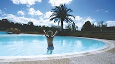 夏日阳光明媚，一个年轻女孩在度假村的户外游泳池里玩耍