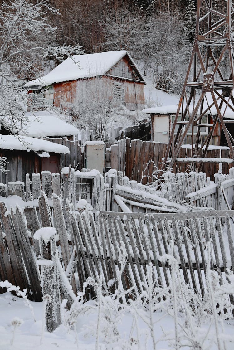 
Snow Covered Houses And Wooden Fences