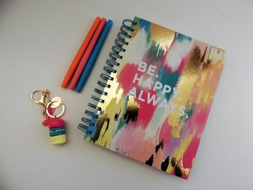 Be Happy Always Spring Notebook Beside Three Assorted-color Pens