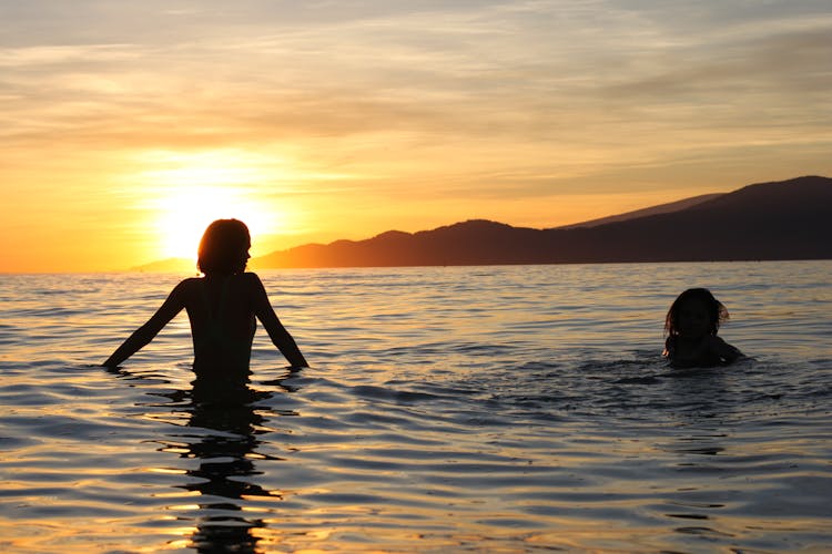 Woman And A Child Swimming At Sunset 