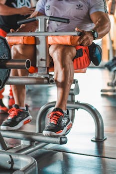 Adult man working out on a leg exercise machine in a modern indoor gym.
