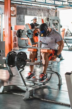 Adult man performing strength training on gym equipment, focused on fitness and endurance.