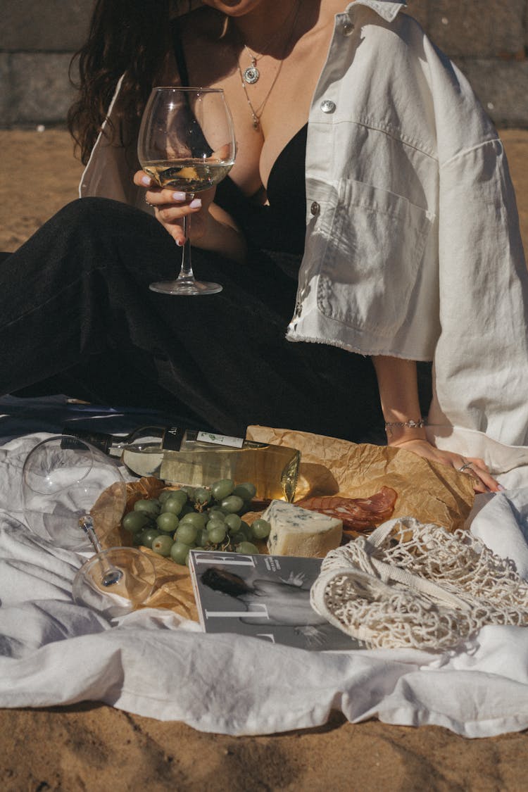 Woman In Black Dress With White Jacket Holding A Glass Of Wine