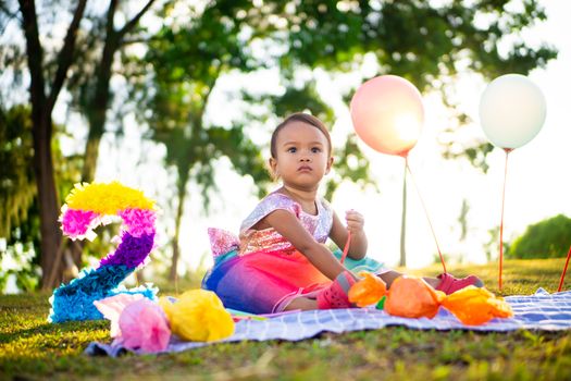 A toddler enjoys a vibrant birthday celebration outdoors with balloons and decorations.