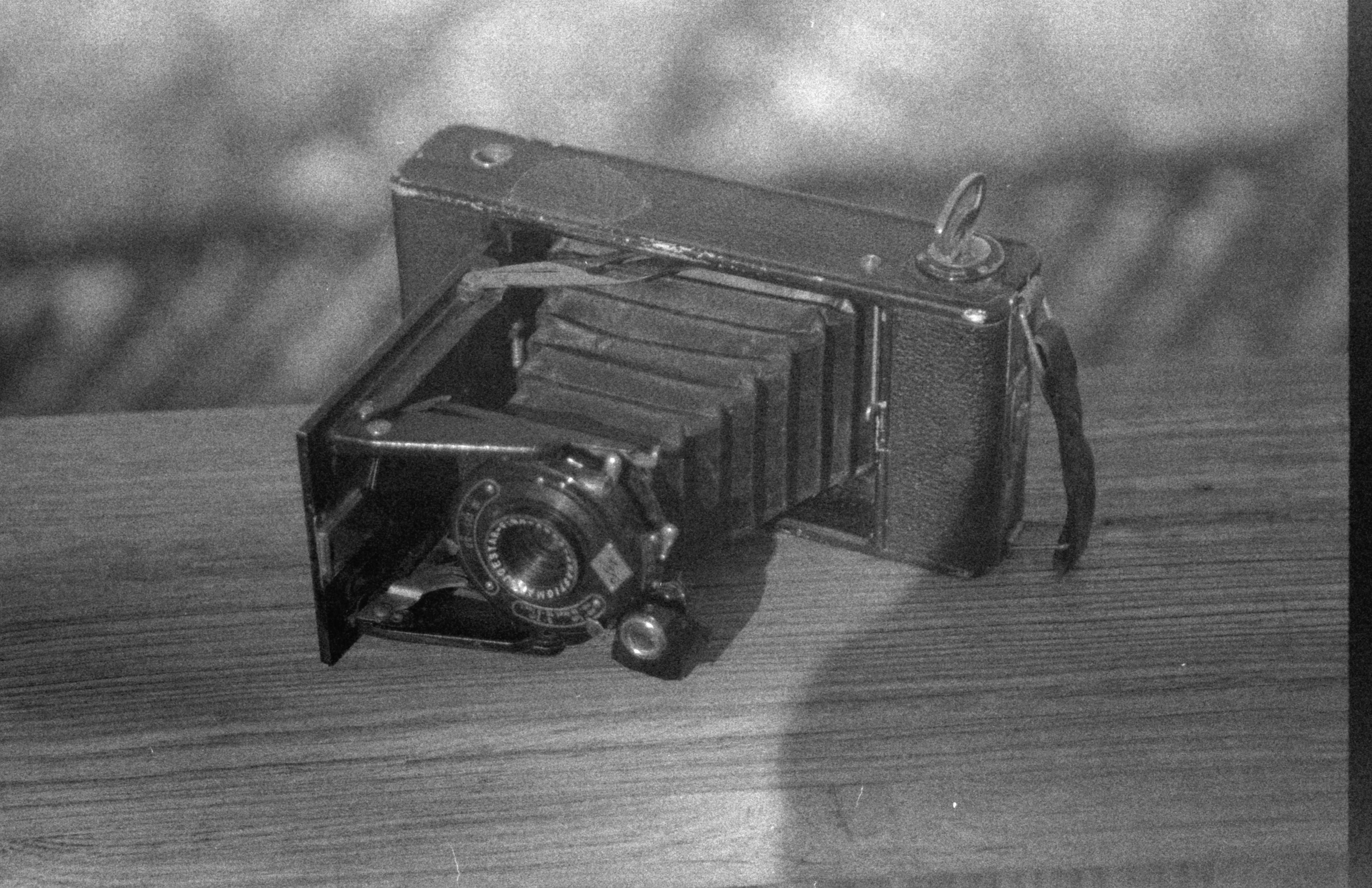 Close-up of a vintage foldable camera on a wooden table, classic and timeless.