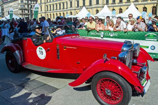 Classic red convertible at Sachsen Classic with spectators in Leipzig, Germany.