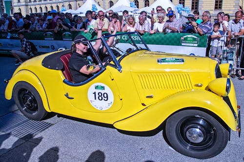 Two People Riding a Yellow Classic Car