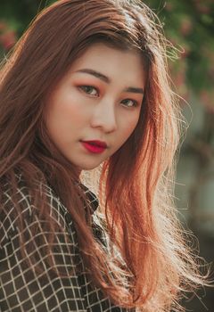 Portrait of an attractive woman with long red hair in natural sunlight, highlighting her beauty and expression.