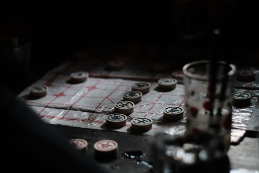 Close-up of a Chinese chess game in dark ambiance with selective focus on pieces.