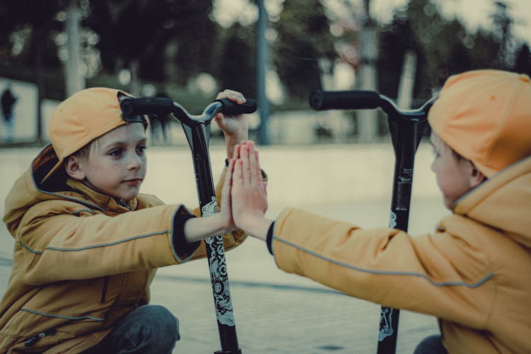 Boy In Orange Hoodie Jacket Looking At His Reflection On The Mirror 