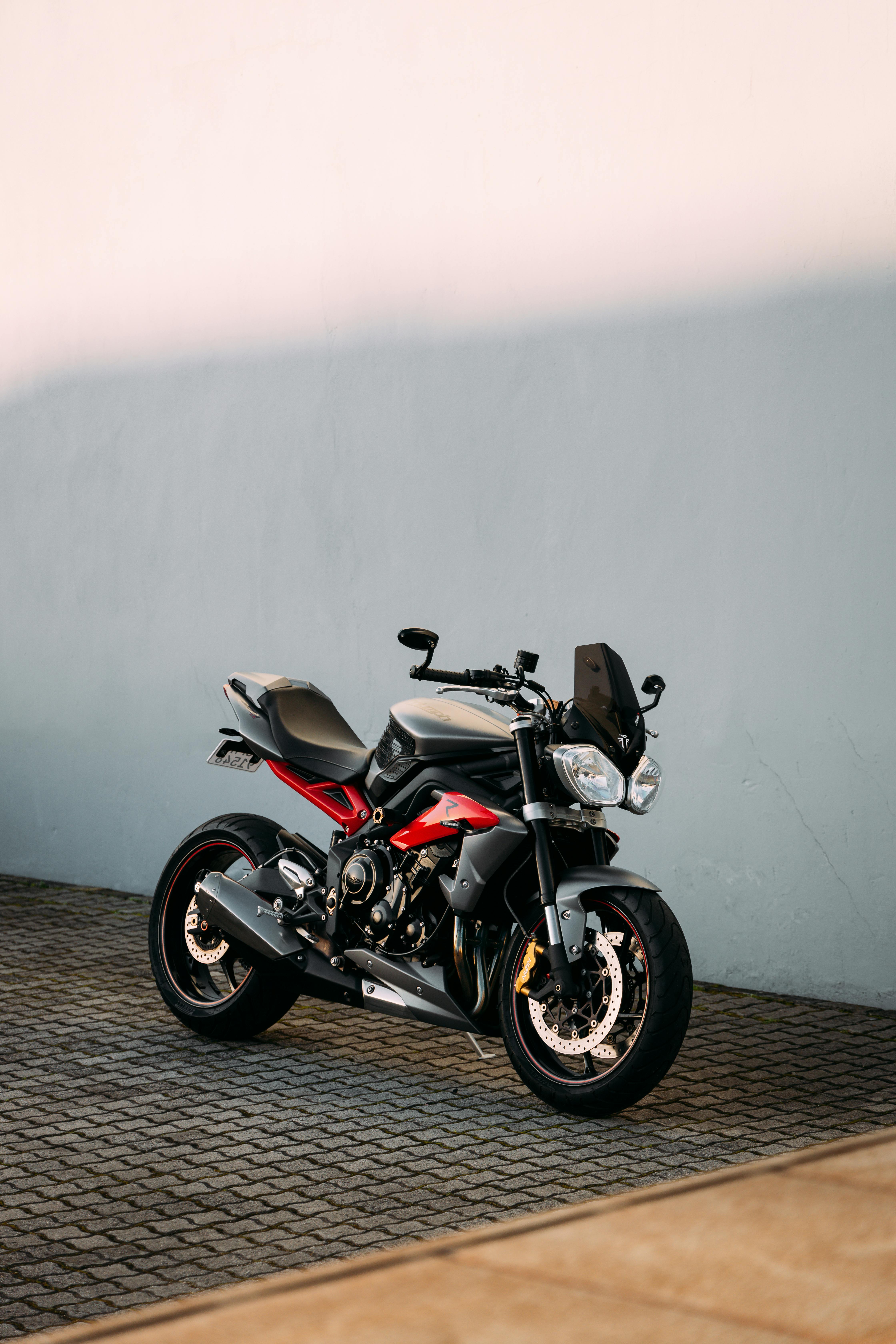 A sleek Triumph motorcycle parked outdoors against a simple clean background.