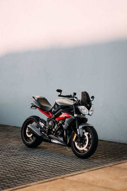 A sleek Triumph motorcycle parked outdoors against a simple clean background.