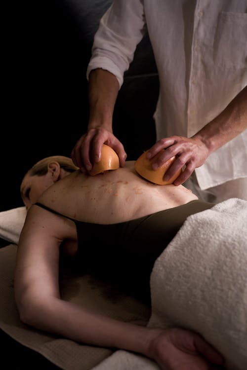 A Masseur Using Grapefruit on an Elderly Woman's Back