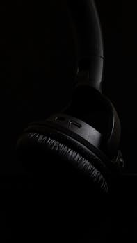 Minimalist close-up of black over-ear headphones against a dark background, showcasing modern design and sleek aesthetics.