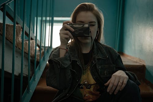 Woman Sitting on Stairs while Holding a Camera