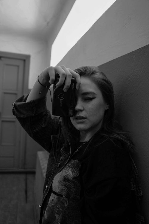 Free Artistic black and white portrait of a woman using a vintage film camera indoors. Stock Photo