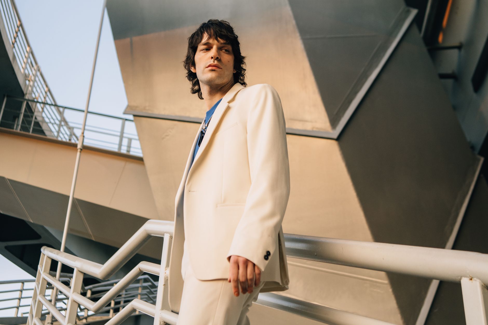 Portrait of a stylish man in a beige suit with architectural backdrop, capturing modern fashion elegance.