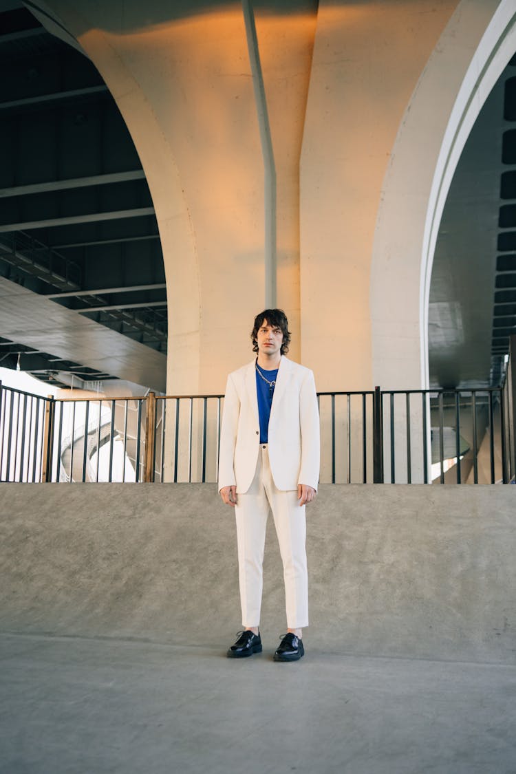 A Man In White Suit And Pants Standing On A Concrete Floor