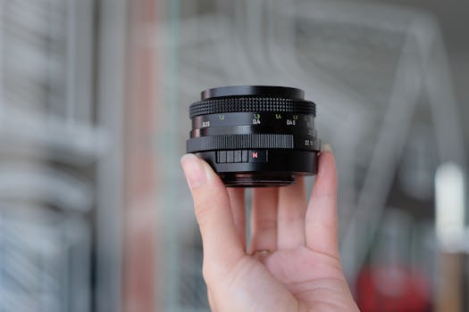 Detailed view of a hand holding a camera lens with blurred background.