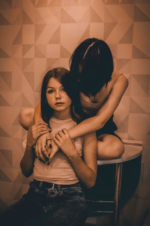 Free Two young women embrace affectionately, creating a tender moment indoors. Stock Photo