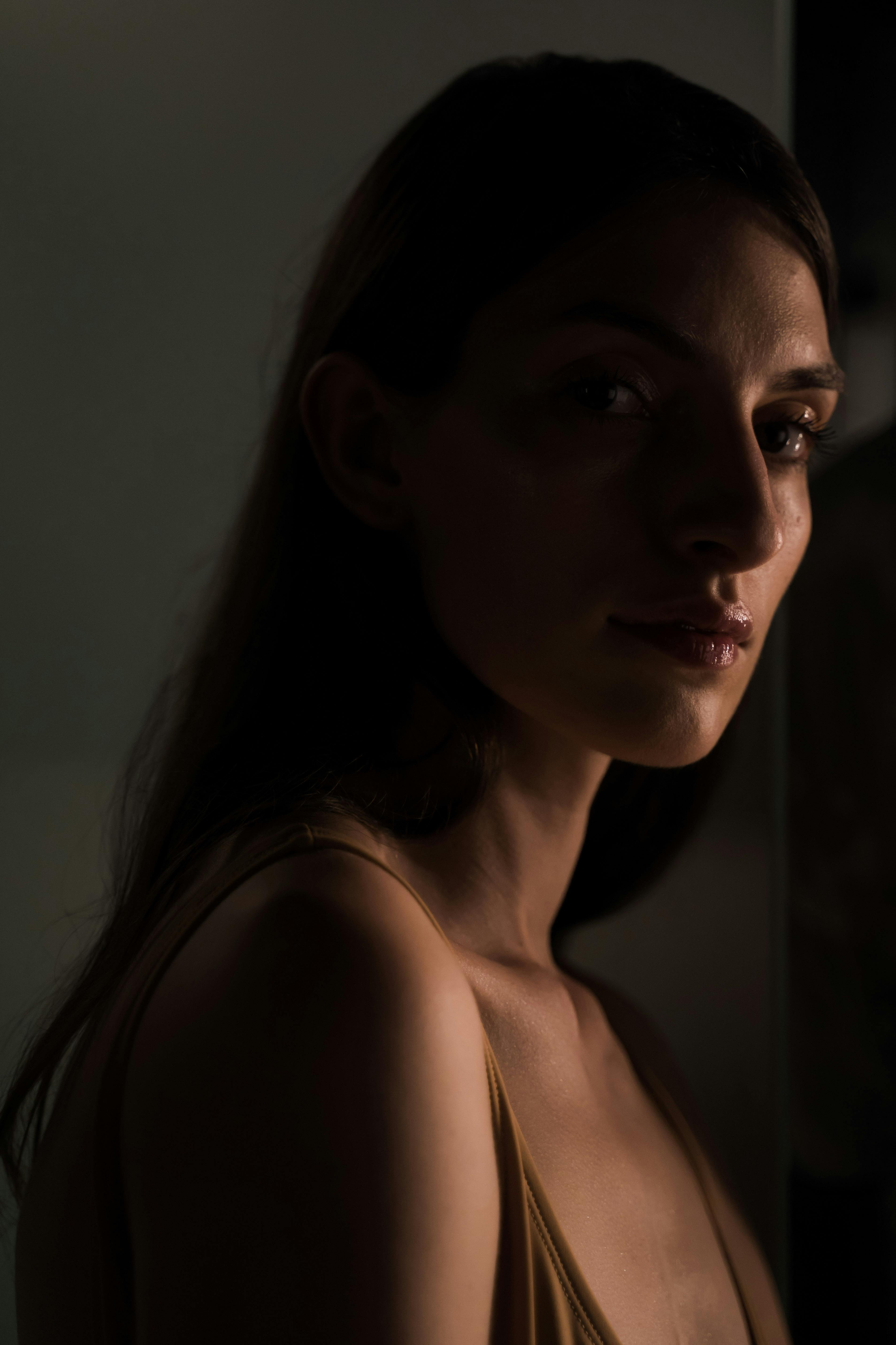 A close-up portrait of a woman in low light, conveying a mysterious and intriguing mood.