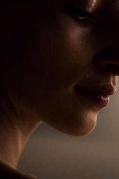 Artistic profile of a woman in shadowed lighting, highlighting her lips and chin.