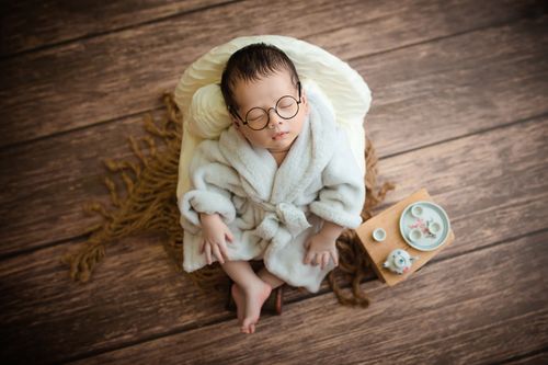 Free A charming newborn sleeping peacefully in a bathrobe with cute eyeglasses, depicting innocence and tranquility. Stock Photo