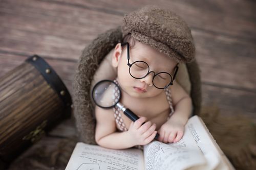 Free Cute newborn sleeping with glasses and book, evoking innocence and curiosity in a studio setting. Stock Photo