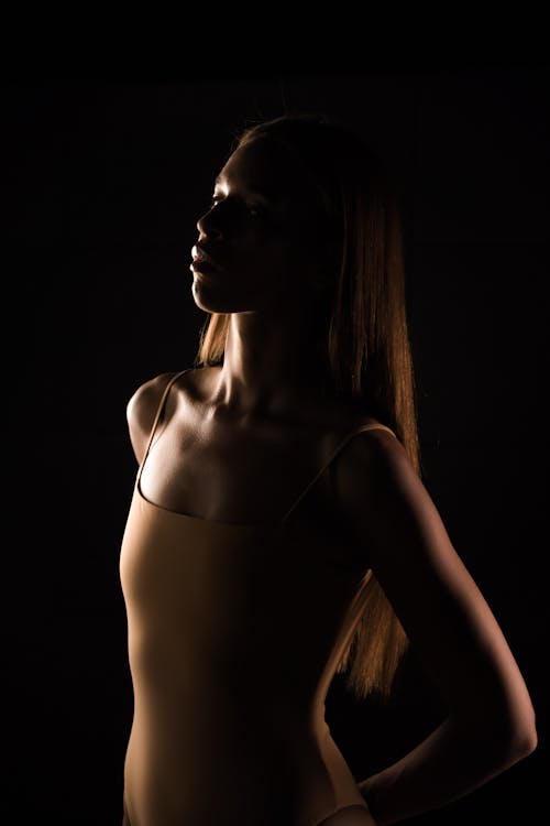 A Woman in Swimsuit Standing Against Black Background