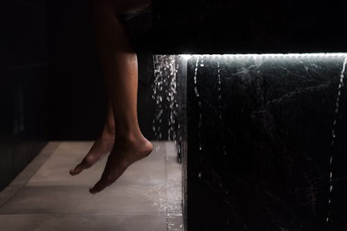 A Person's Feet Near the Dripping Water