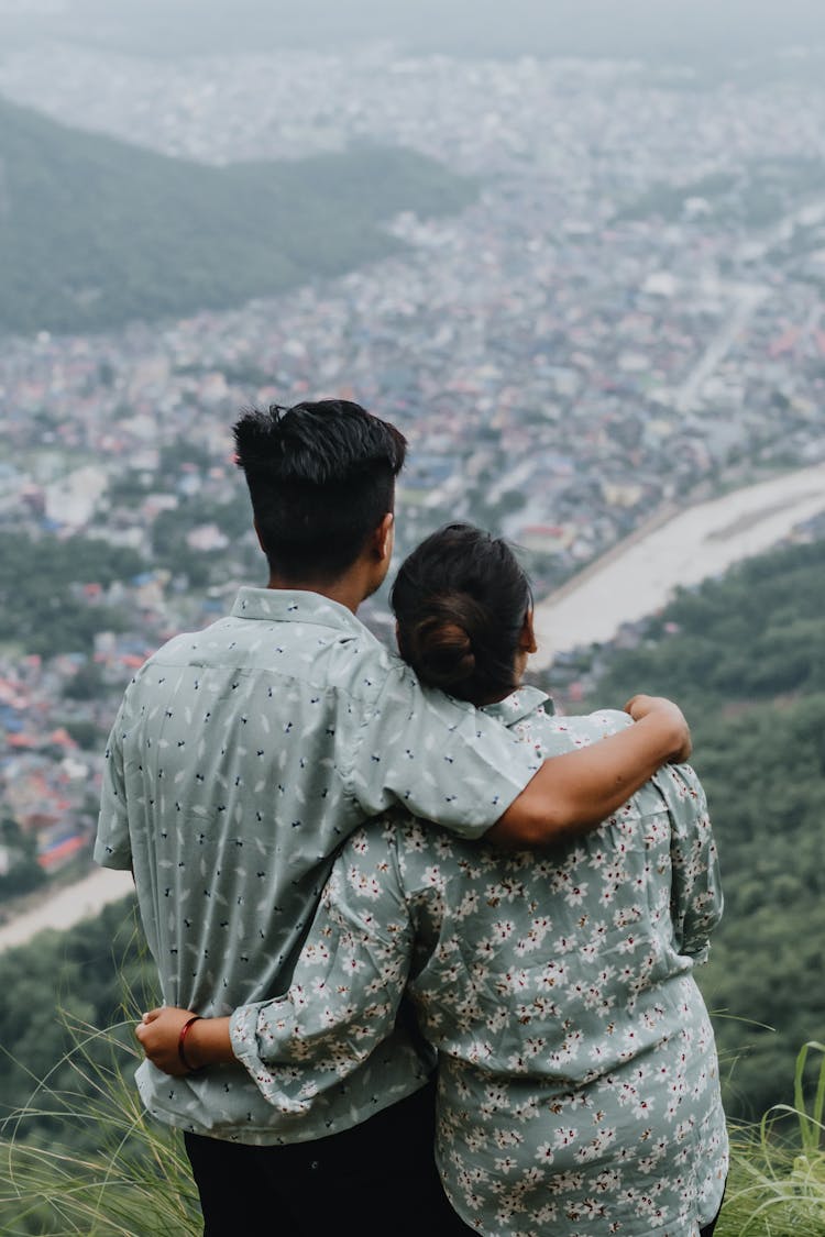 A Back View Of A Couple In Printed Shirt Embracing Each Other While Looking At The View