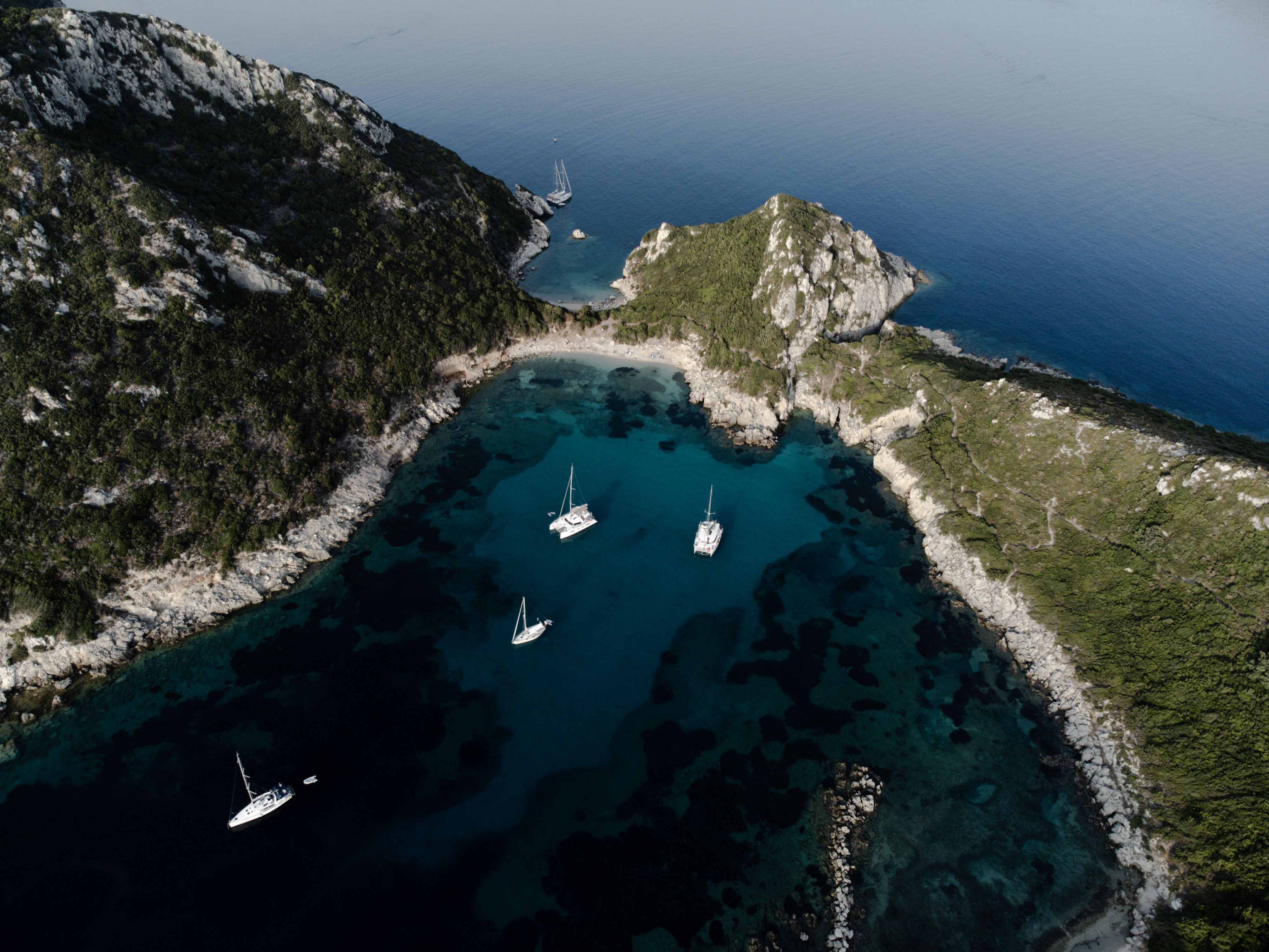 Best Luxury Symi Cruise & St. George's Bay (Only ~1-hour journey) Review: The Ultimate Greek Island Escape Review 2026 - Aerial view of serene bay in Kerkira, Greece with sailboats and rocky coastline.
