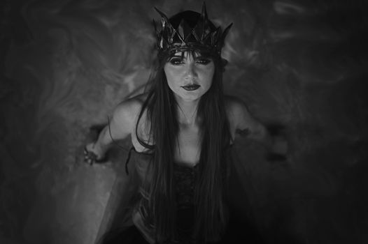 Dramatic black and white portrait of a woman in a crown and gown, exuding elegance and mystery.