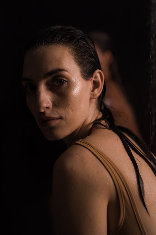 Free A captivating low-light portrait of a woman with wet hair and a contemplative gaze. Stock Photo