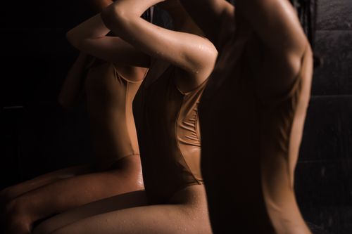 Free A group of women wearing brown swimwear under a shower indoors, creating a moody and intimate atmosphere. Stock Photo