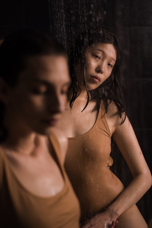 Free Intimate portrait of two women in swimsuits under a shower, creating a serene spa-like ambiance. Stock Photo