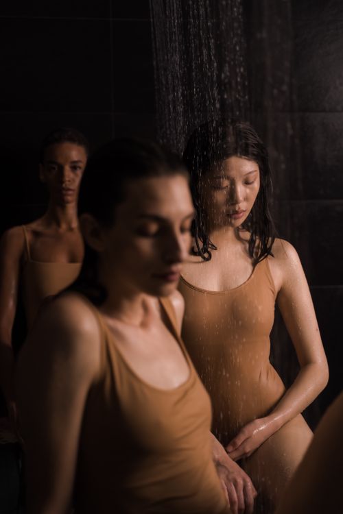 Free A dramatic and moody shower scene featuring women in fashion bodysuits. Captured with style. Stock Photo