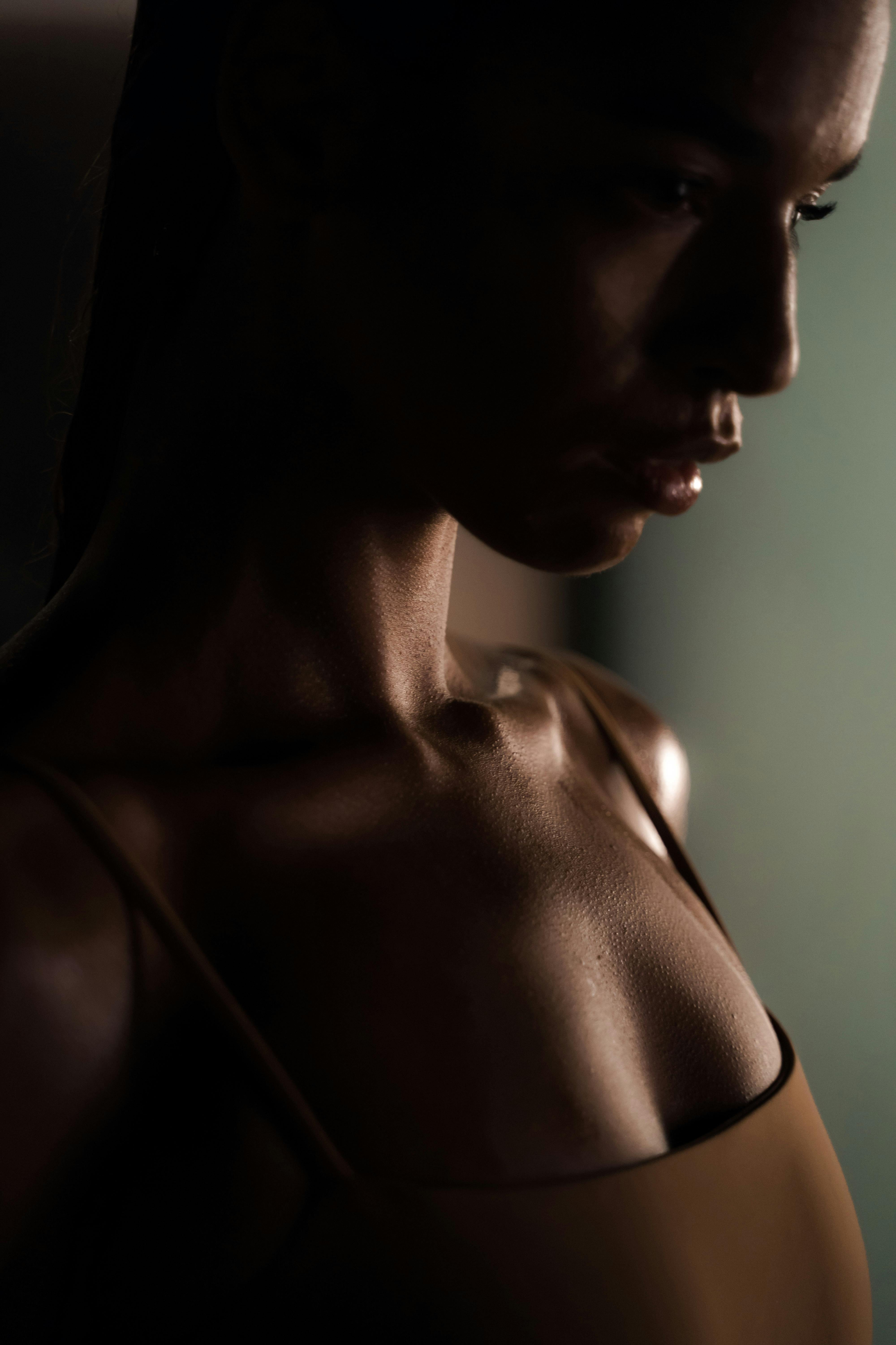 Moody and artistic side profile portrait of a woman in low light, highlighting contours.