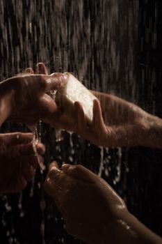 Artistic shot focusing on hands under streaming water lathering with soap, conveying hygiene and cleanliness.