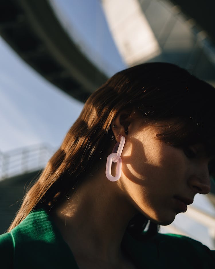 A Brunet Woman With A White Interlocking Earing Wearing Green Jacket