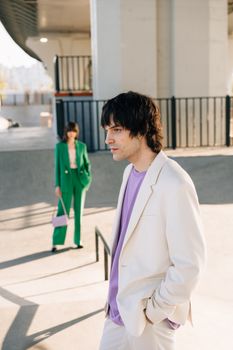 Models in vibrant suits pose stylishly in an urban street setting.