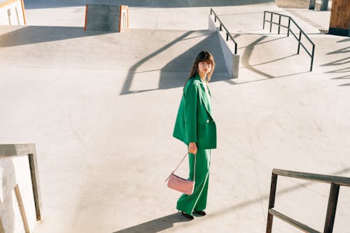 Model in a Green Suit Carrying a Pink Handbag