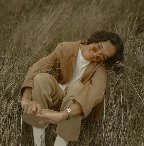 Free Young man in a stylish brown outfit posing confidently in a grass field. Stock Photo