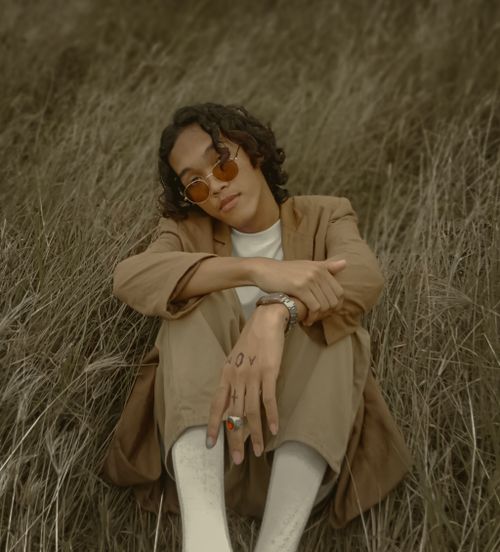 Free Stylish young man in sunglasses and suit posing outdoors in the grass. Unique fashion and personal style captured. Stock Photo